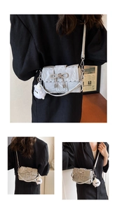 Détail de la sacoche argentée plissée avec un nœud en strass et un petit pendentif