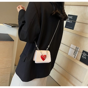 Close-up of mini crossbody bag with red heart detail and wavy edge on a shoulder strap