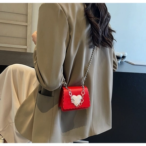 Detail of red leather mini bag with large white heart and silver chain on model