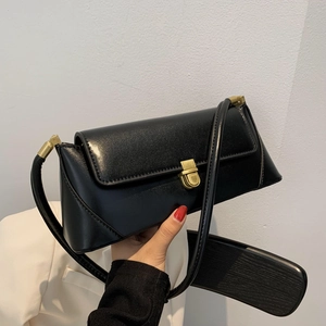 Minimalist black faux leather underarm bag with gold buckle on white suit background