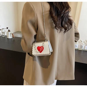 Close-up of silver metallic mini bag with red heart pattern and ball chain strap
