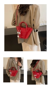 Detail of red glossy trapezoid bucket bag with silver bow pearl charm and brand logo