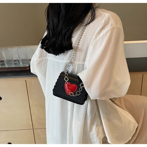 Detail of black mini crossbody bag with red heart pattern and silver chain strap