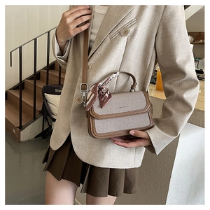Detail of canvas and leather contrast handbag with silk scarf wrap on handle and shoulder strap