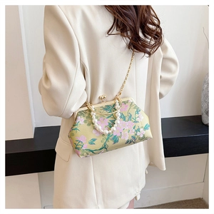 Detailed view of vintage shell bag with floral embroidery and large pearl handle strap