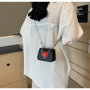 Mini black crossbody bag with red heart and silver flower chain on white shirt