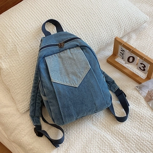 Chic blue denim mini backpack with contrast pocket resting on a cozy pillow