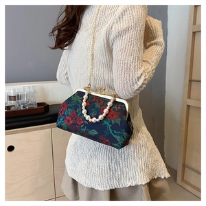 Detailed view of retro shell bag with floral fabric, pearl handle and metal chain strap