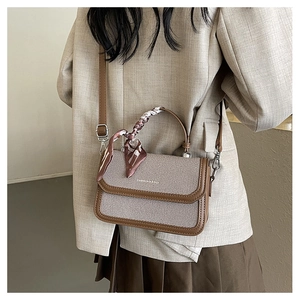 Detail of a brown and khaki patchwork crossbody bag with decorative floral silk scarf