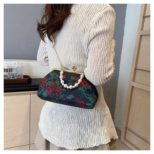 Detailed side view of vintage navy shell bag with floral embroidery and pearl handle