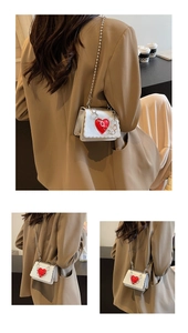 Detail of silver mini chain bag featuring a red heart patch with Hand Made engraving