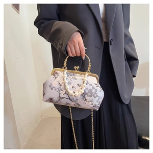 Detail of vintage floral shell bag with pearl handle and golden metal chain strap