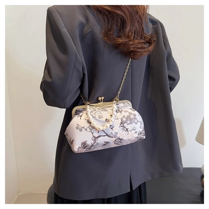 Detail of vintage floral silk shell bag with pearl handle worn on dark blazer