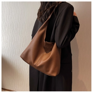 Detail of a large brown leather hobo bag showing soft lychee texture on a shoulder