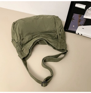 Detail of army green canvas crossbody bag with multi-pocket design and adjustable strap