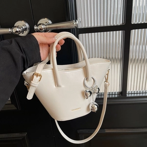 Minimalist cream leather bucket handbag with gold logo and silver bow charm detailing