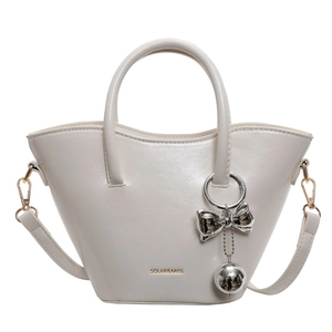 Creamy white PU leather bucket bag with top handles, crossbody strap, and bow charm
