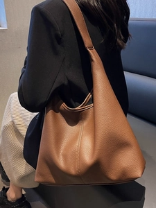Brown large-capacity leather tote bag with lychee texture shown on model shoulder