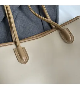 Detailed view of dual stitching on beige and brown tote bag with high-quality faux leather
