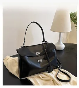 Détail d'un cabas en cuir noir avec serrure rotative argentée dans un bureau à domicile