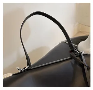 Gros plan du sac cabas en cuir noir avec anneaux argentés et poignée robuste de qualité
