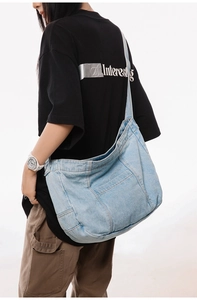 Detail of light blue denim crossbody bag featuring large capacity and wide shoulder strap