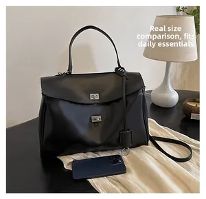 Détails d'un grand sac à main noir en cuir avec fermoirs métalliques et taille réelle