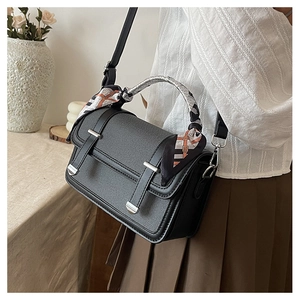 Detail of black crossbody bag with silk scarf wrapped handle and silver buckles