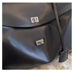 Détail du sac cabas en cuir noir texturé avec doubles verrous rotatifs en métal argenté