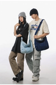 Dual models wearing large washed denim messenger bags in light and dark blue styles