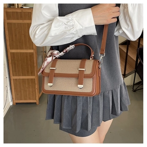 Detailed view of crossbody bag with brown leather, canvas front, and scarf handle