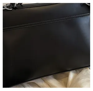 Gros plan sur la texture en cuir PU noir et le détail de la chaîne argentée du sac