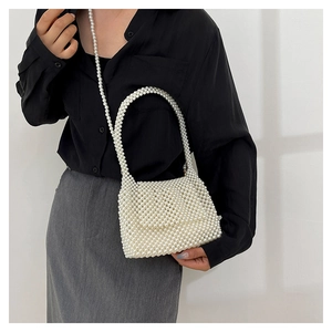 Détail d'un sac à main en perles blanches avec bandoulière porté par un mannequin
