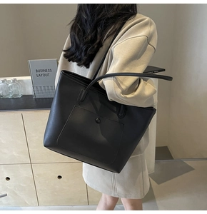 Detail of minimalist black tote bag with matte texture and decorative studs on shoulder strap