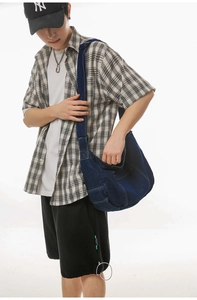 Detail view of large capacity dark blue denim crossbody bag with exterior pocket
