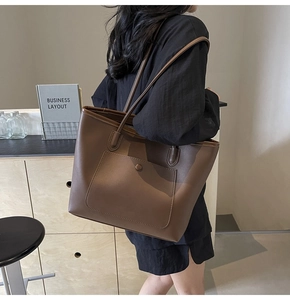 Brown leather tote bag featuring a front pocket shown in a chic cafe setting