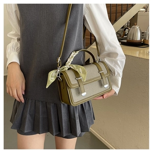 Detail of green leather crossbody bag with woven fabric texture and silk scarf handle