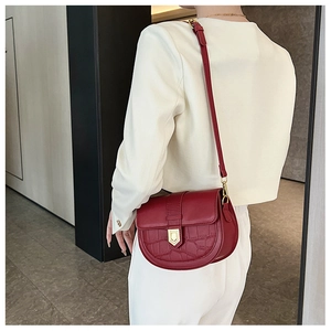 Detail of burgundy saddle bag showing crocodile embossed leather and gold buckle