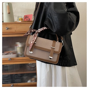 Close-up of vintage canvas messenger bag with brown leather trim and scarf handle