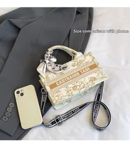 Detailed view of canvas tote bag size compared to a phone with jacquard strap
