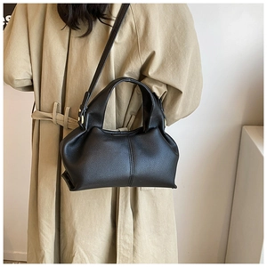 Detail of black pebbled leather handbag featuring soft folds and gold metallic hardware