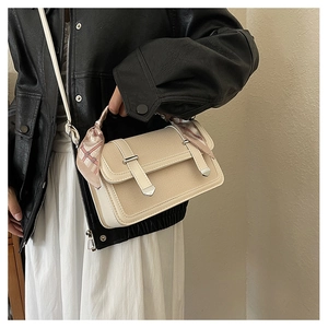 Close-up of beige canvas crossbody bag with leather trim and pink silk scarf on handle