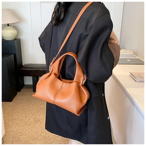 Brown orange leather cloud bag worn by a model in a modern office or home office setting
