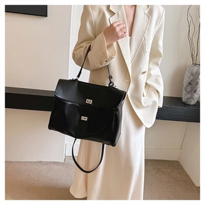 Détail d'un grand sac cabas en cuir noir avec des fermoirs argentés portés par un modèle
