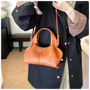 Close-up of brown leather crossbody bag with pleated texture and adjustable shoulder strap