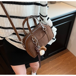 Detail of retro suede Boston bag featuring baseball charm and adjustable strap