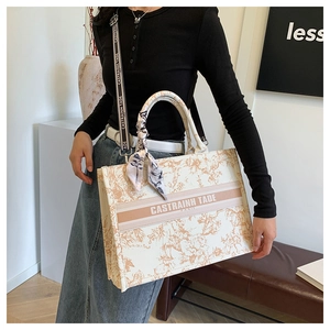 Close-up of floral beige tote bag with a branded shoulder strap and silk scarf handle