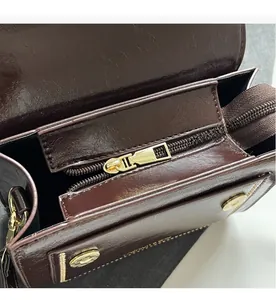 Close-up of golden rectangular metal zipper and interior pocket on brown leather bag