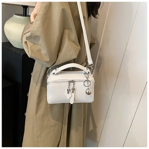 Gros plan du petit sac carré blanc avec motif litchi et pendentif boule en métal argenté