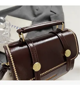 Close-up of vintage brown leather bag with gold rivets and logo on fashion background